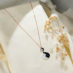 Angled view of black and white beaded yin-yang pendant with rose-gold yin-yang disc on silk